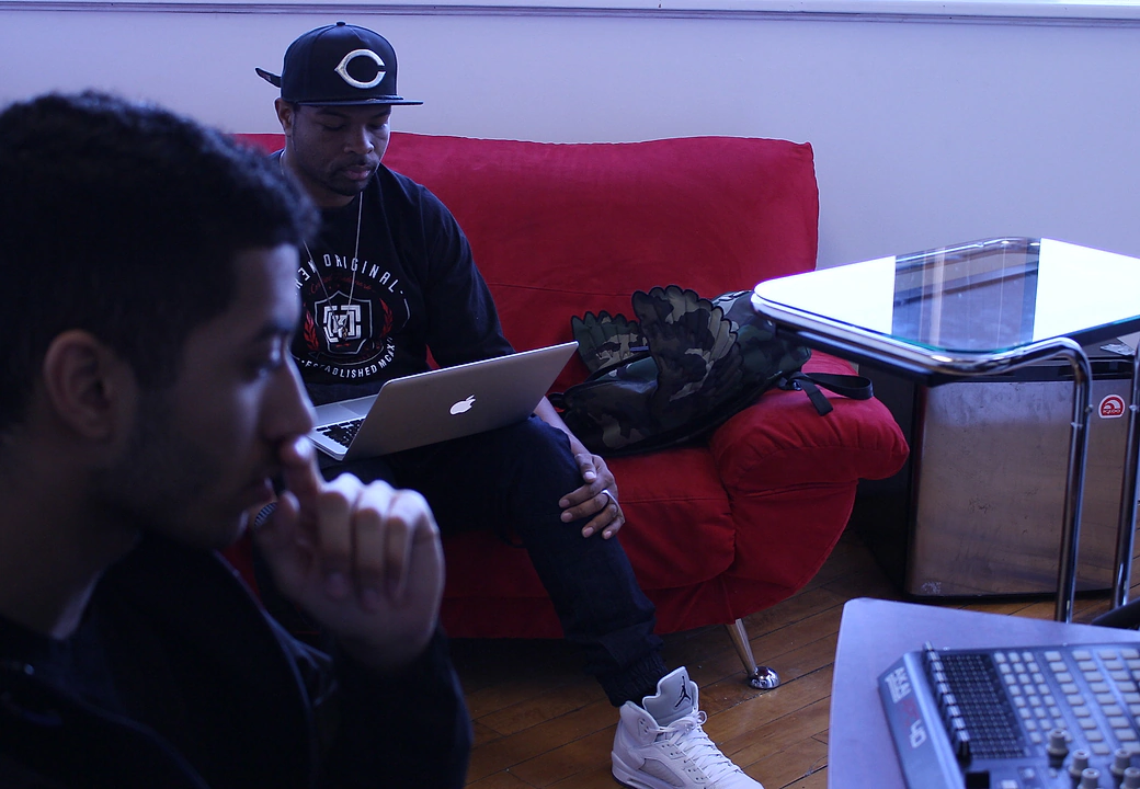 Two creators in the Gifted Studios lounge — one on a laptop on the red sofa