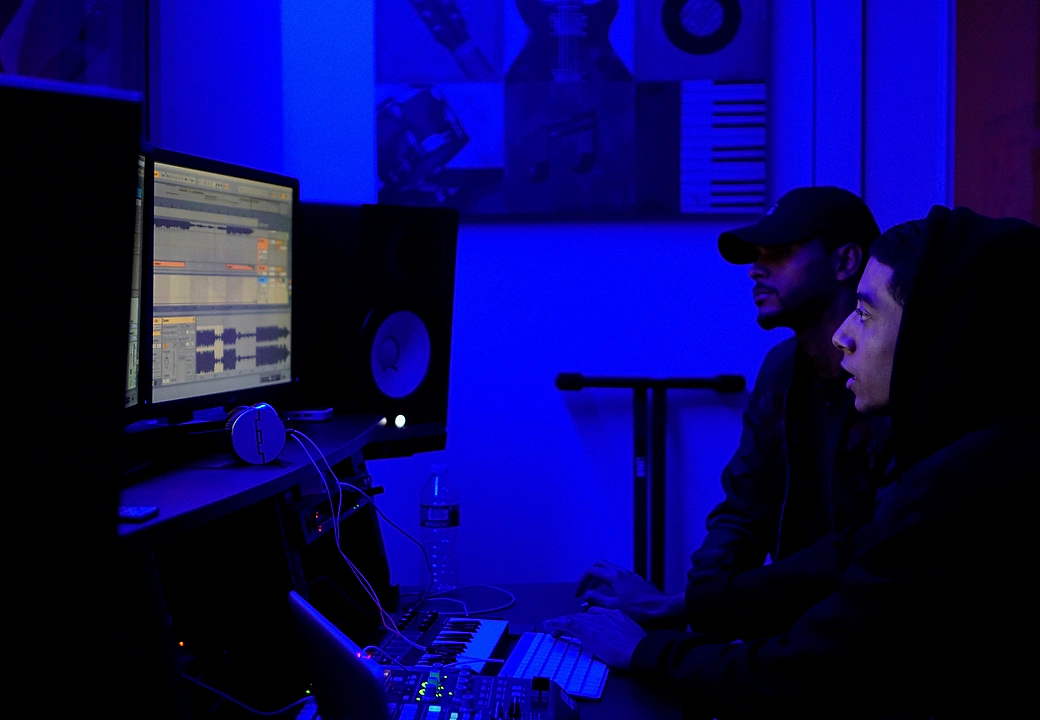 Two producers focused on dual monitors in the blue-lit Gifted Studios room