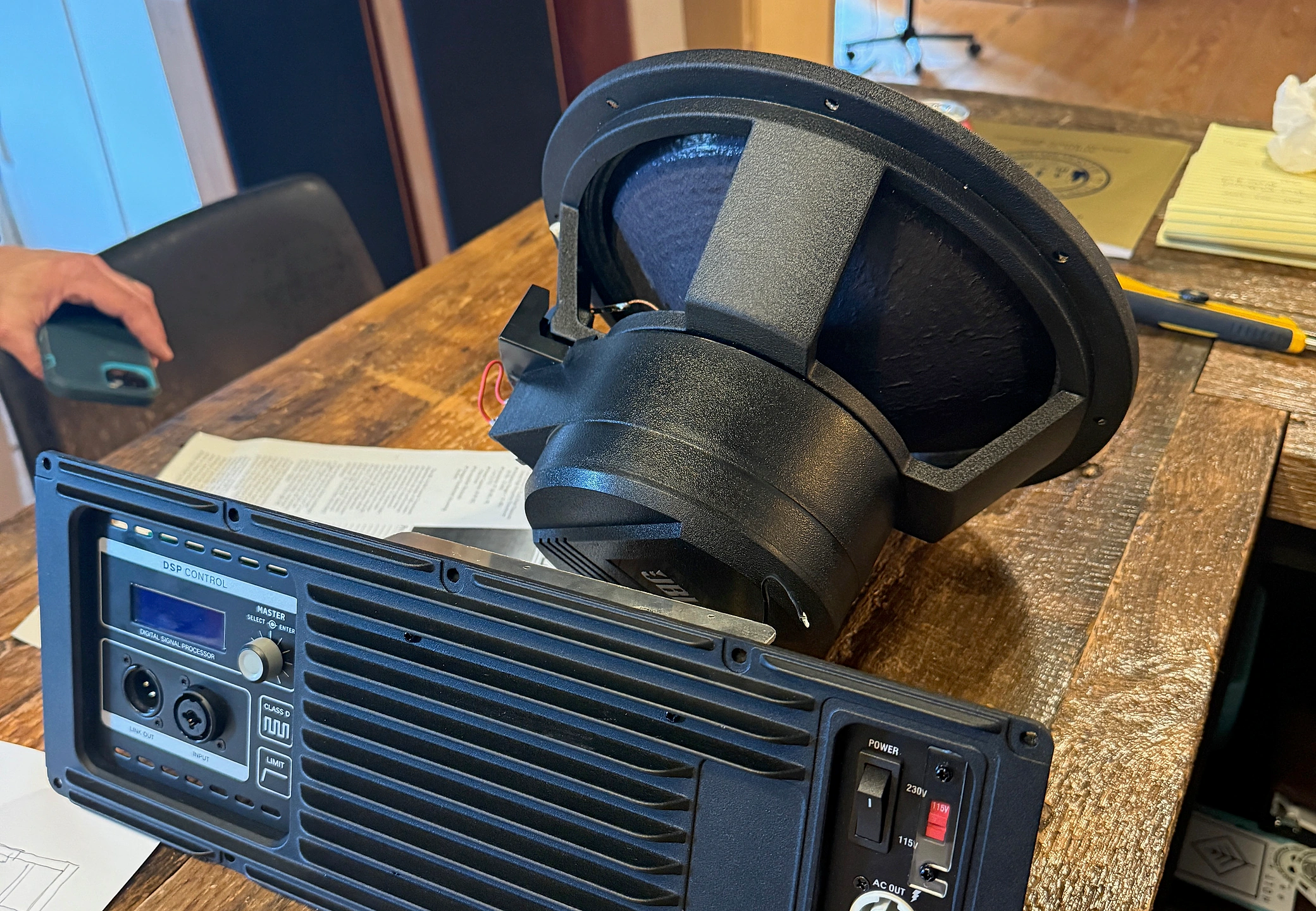 Amplifier back panel and speaker driver laid out on a workshop table