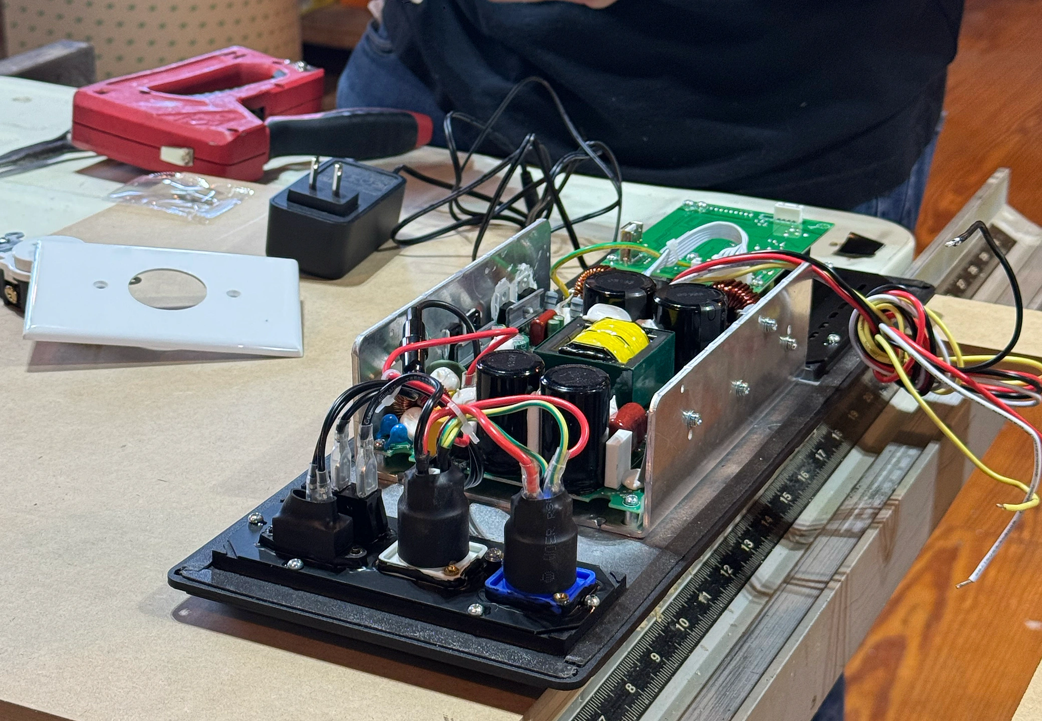Hands assembling the speaker electronics — capacitors, transformer, and colored wiring on the chassis