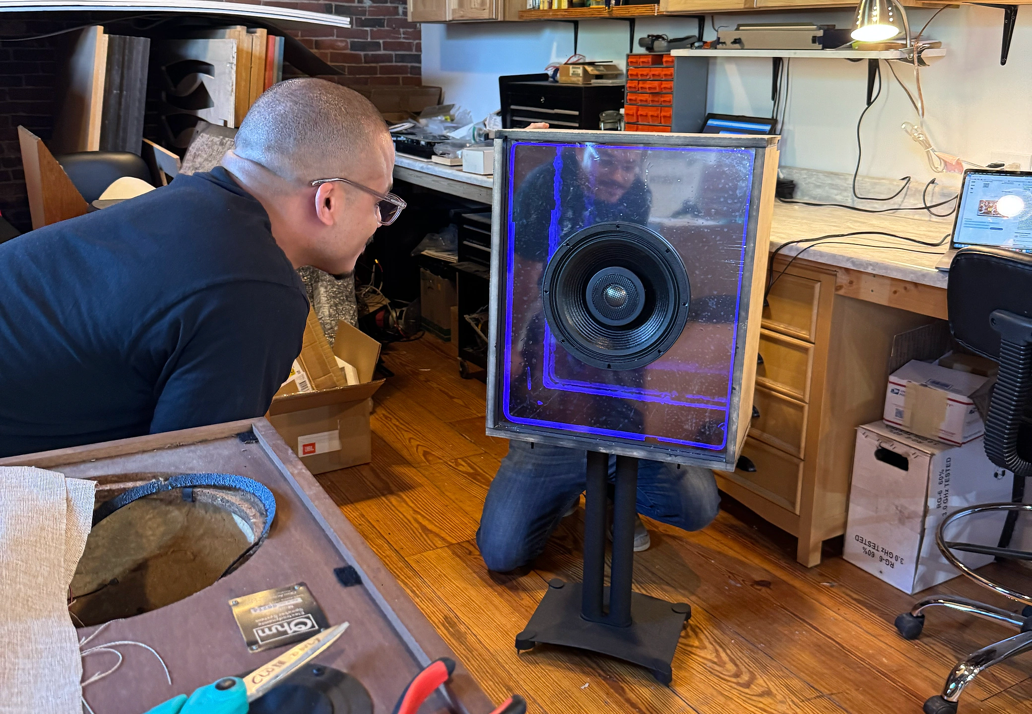 Inspecting the standing prototype — blue infinity glow lit in the workshop