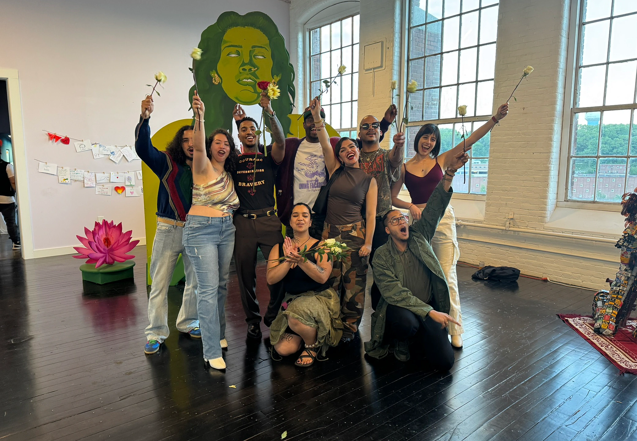 Group photo with the cohort against the yellow mural at the show